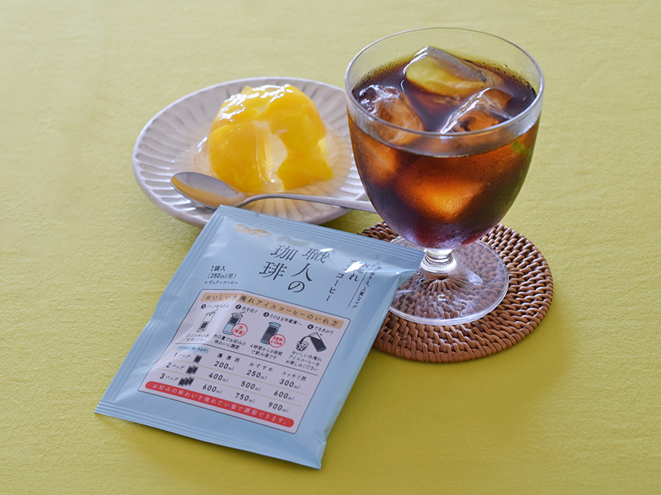 UCC職人の珈琲水淹れアイスコーヒーのパックとマンゴーゼリーとコーヒーが入ったグラスをセットで写した写真