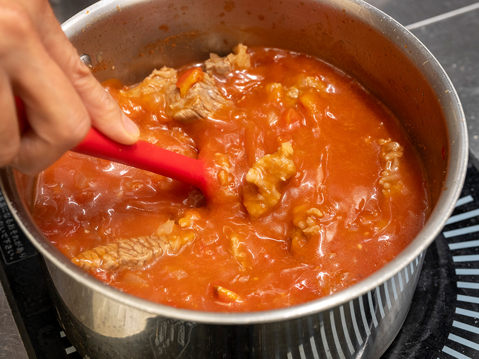 カレーを混ぜながら煮込んでいる