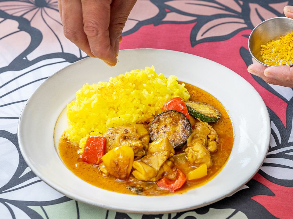 盛り付けられたカレー レモンライスにレモンピールを振りかけている