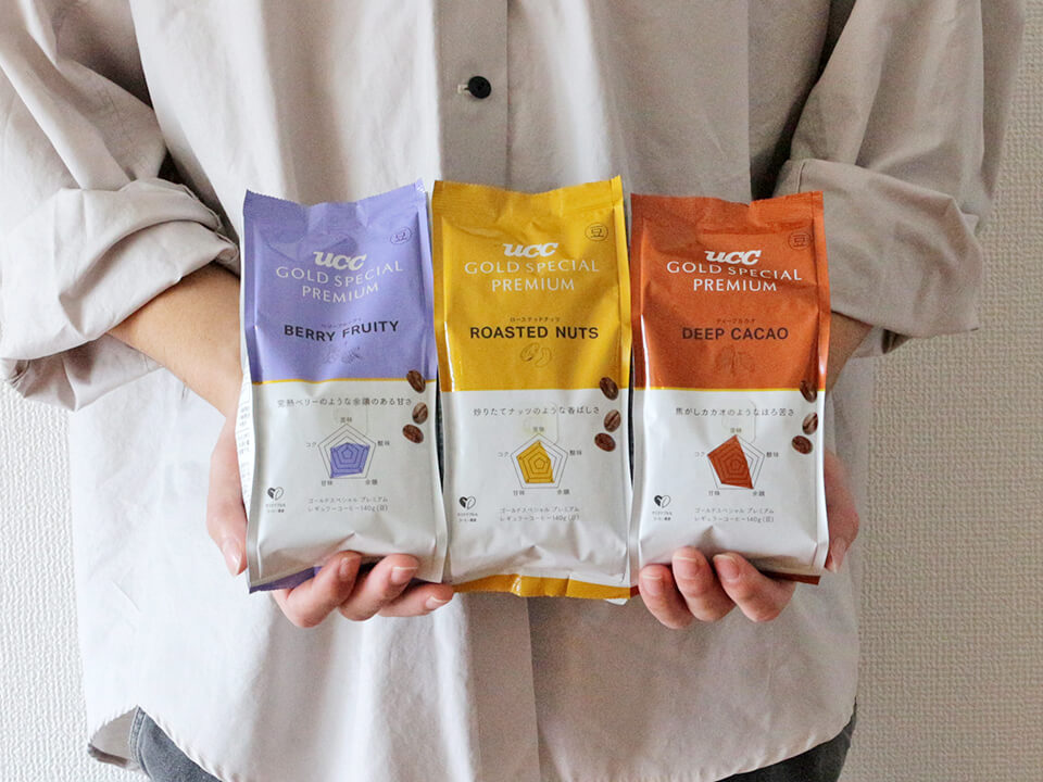 UCC GOLD SPECIAL PREMIUM BERRY FRUITYとROASTED NUTSとDEEP CACAOを持っている様子